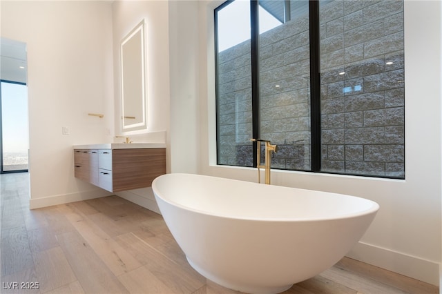 bathroom with a bathing tub, wood-type flooring, plenty of natural light, and vanity