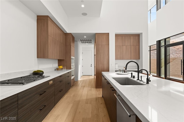 kitchen with visible vents, light wood-style flooring, appliances with stainless steel finishes, a sink, and modern cabinets