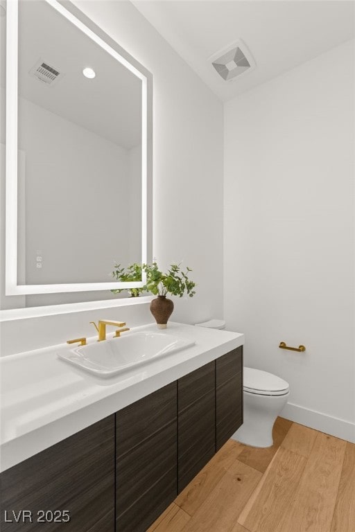 bathroom featuring visible vents, vanity, toilet, and wood finished floors