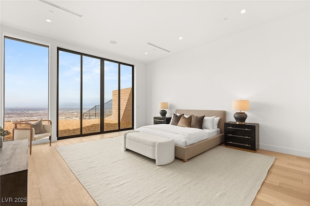 bedroom featuring light wood finished floors, expansive windows, baseboards, and recessed lighting