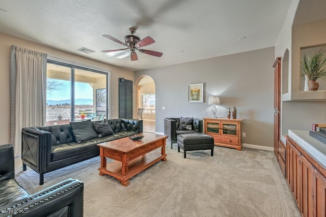 carpeted living room with ceiling fan and a textured ceiling