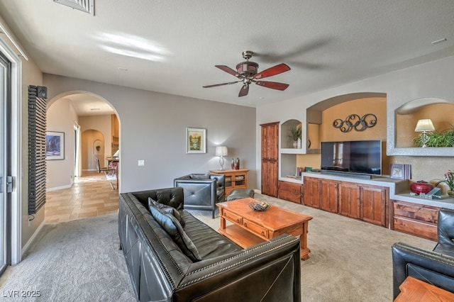 living room featuring light carpet, a textured ceiling, and ceiling fan