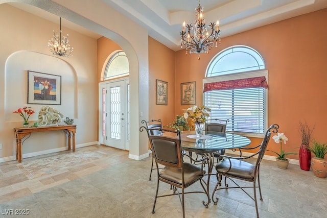 dining area featuring a notable chandelier, a towering ceiling, and a raised ceiling