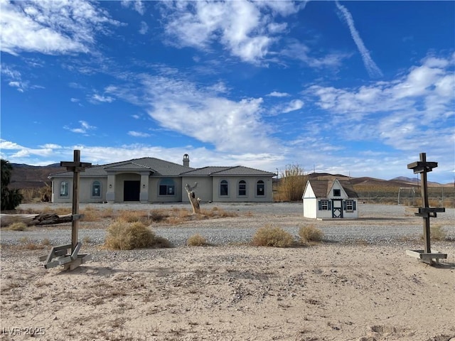 view of front of house with a storage shed and a mountain view