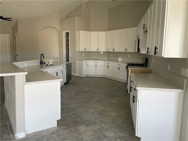 kitchen with sink, ceiling fan, appliances with stainless steel finishes, white cabinetry, and an island with sink