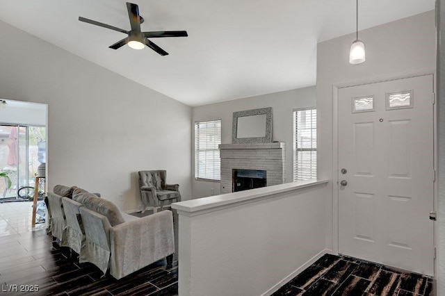 entryway with vaulted ceiling, plenty of natural light, ceiling fan, and a fireplace