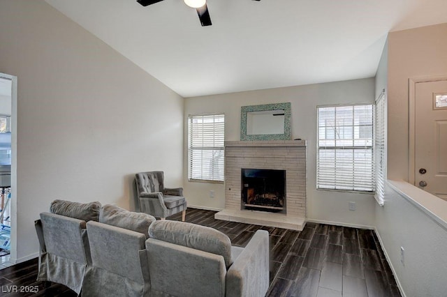 living room with a brick fireplace, vaulted ceiling, and ceiling fan