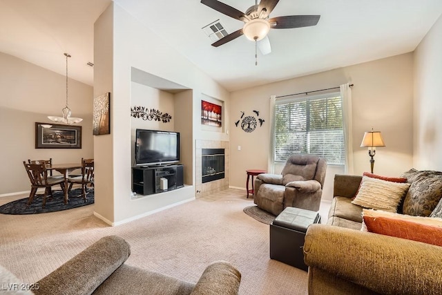 living room with a tiled fireplace, carpet floors, ceiling fan, and vaulted ceiling