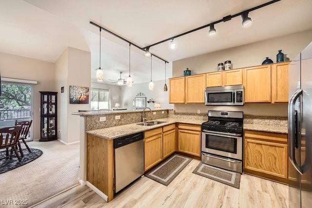 kitchen featuring sink, appliances with stainless steel finishes, light stone countertops, decorative light fixtures, and kitchen peninsula