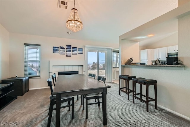 dining space featuring a tile fireplace, a healthy amount of sunlight, vaulted ceiling, and carpet flooring