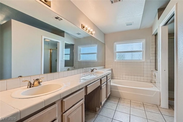 bathroom featuring vanity, shower with separate bathtub, tile patterned flooring, and a textured ceiling