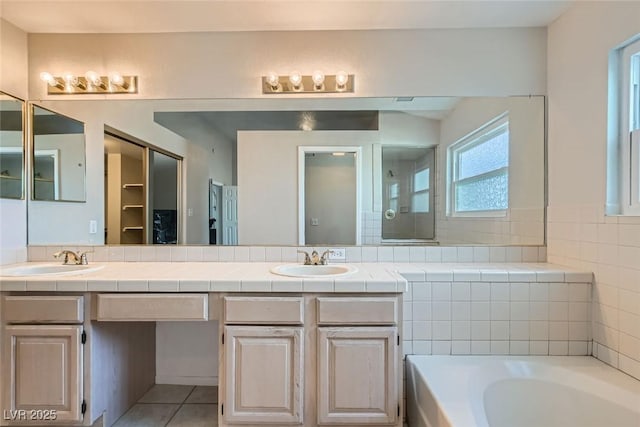 bathroom featuring tile patterned floors, vanity, and a bath