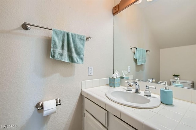 bathroom featuring lofted ceiling, vanity, and toilet