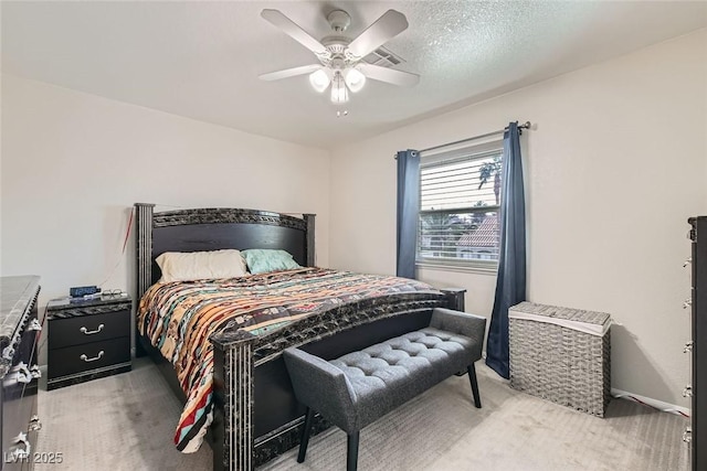 bedroom with ceiling fan, light colored carpet, and a textured ceiling