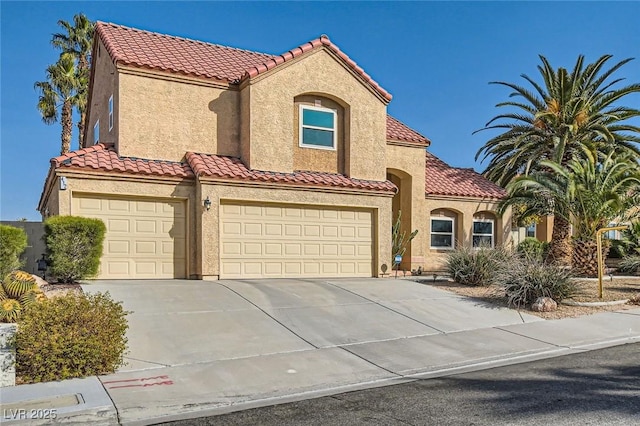 mediterranean / spanish house with a tiled roof, a garage, driveway, and stucco siding