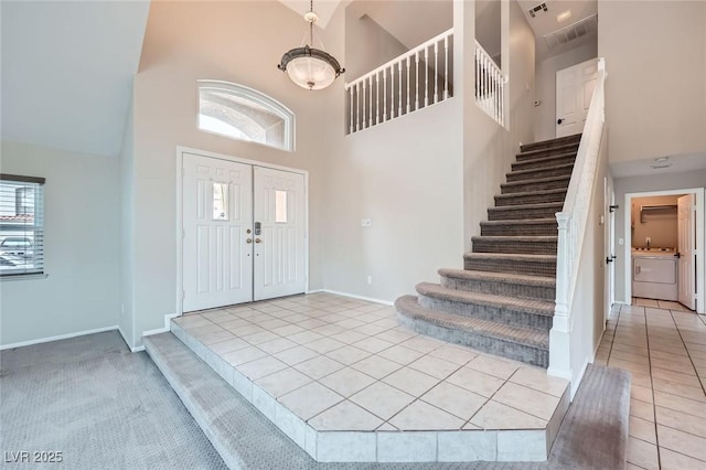 foyer featuring tile patterned flooring, stairway, a high ceiling, and baseboards