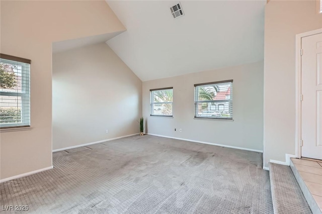 carpeted spare room featuring visible vents, lofted ceiling, and baseboards