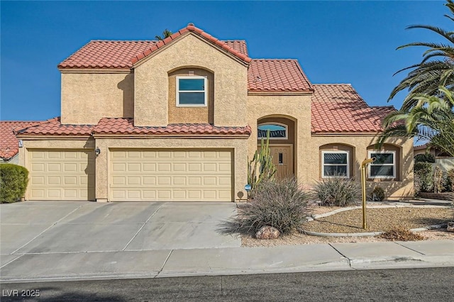 mediterranean / spanish house with a tile roof, a garage, driveway, and stucco siding