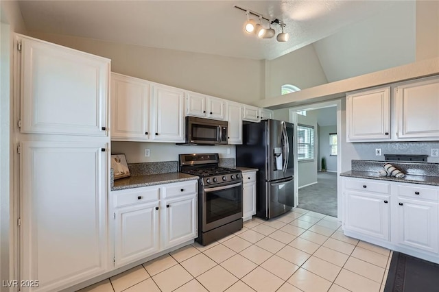 kitchen featuring lofted ceiling, white cabinets, light tile patterned floors, and stainless steel appliances