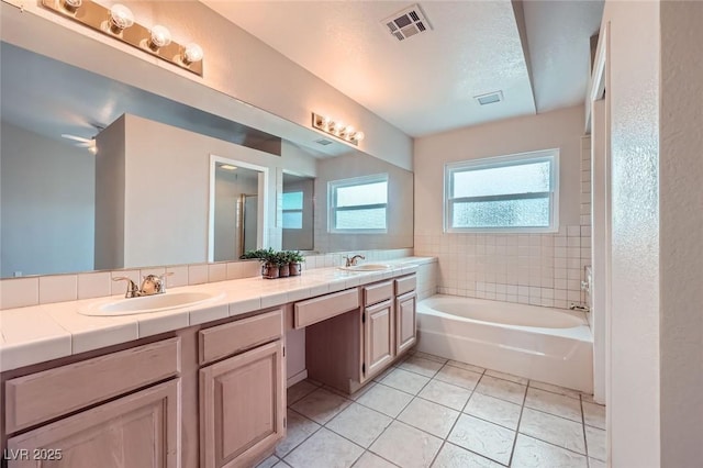 bathroom with a bath, visible vents, tile patterned flooring, and a sink