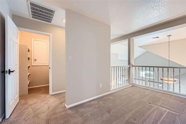 carpeted spare room featuring vaulted ceiling, baseboards, and visible vents