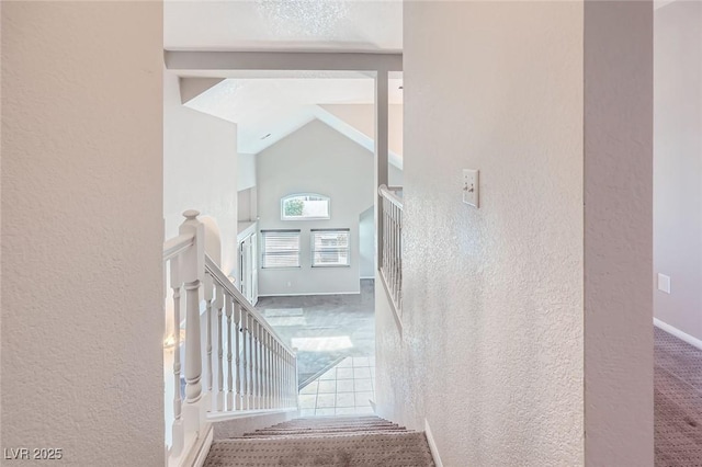 staircase featuring beamed ceiling, carpet floors, high vaulted ceiling, and a textured wall