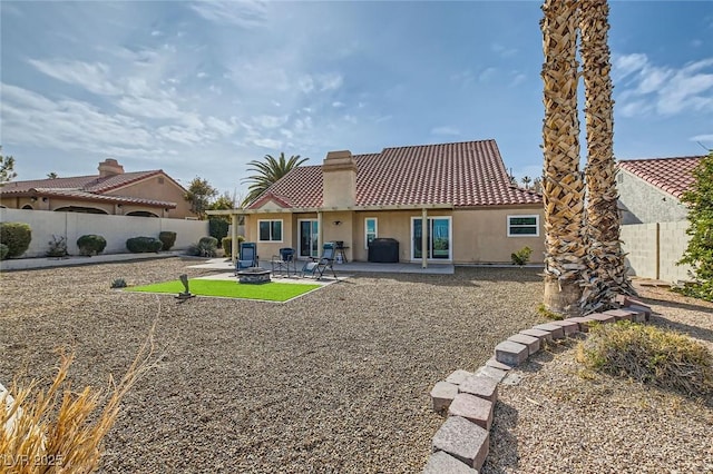 back of property featuring stucco siding, a fenced backyard, a patio area, a chimney, and a tiled roof