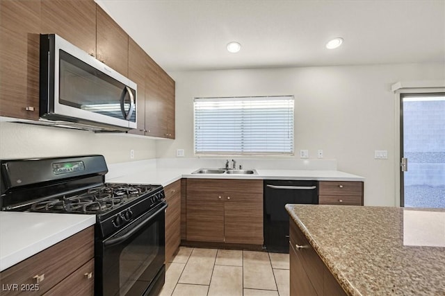 kitchen featuring plenty of natural light, sink, light tile patterned floors, and black appliances