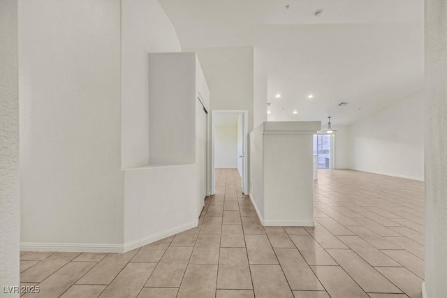 hallway with a chandelier and light tile patterned floors