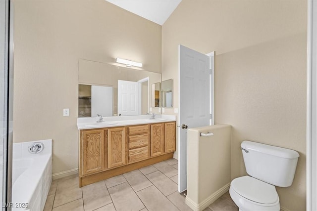 bathroom featuring tile patterned flooring, a tub to relax in, vanity, and toilet