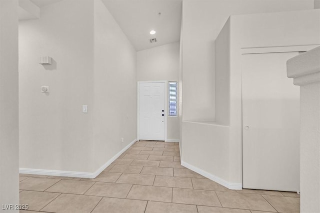 hall with lofted ceiling and light tile patterned floors