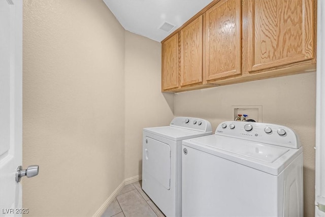 laundry room with cabinets, washing machine and clothes dryer, and light tile patterned flooring