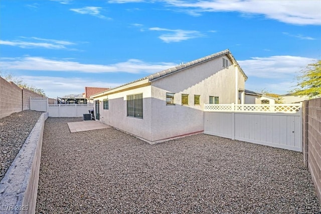 back of property with central AC and a patio