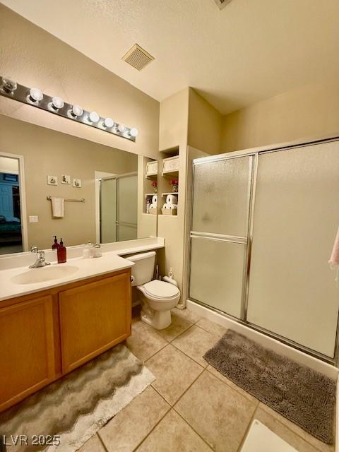 bathroom with tile patterned flooring, an enclosed shower, vanity, and toilet