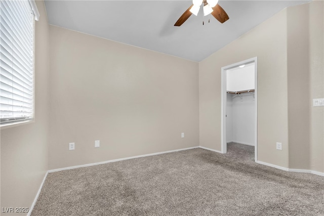 unfurnished bedroom with ceiling fan, vaulted ceiling, carpet, a walk in closet, and a closet