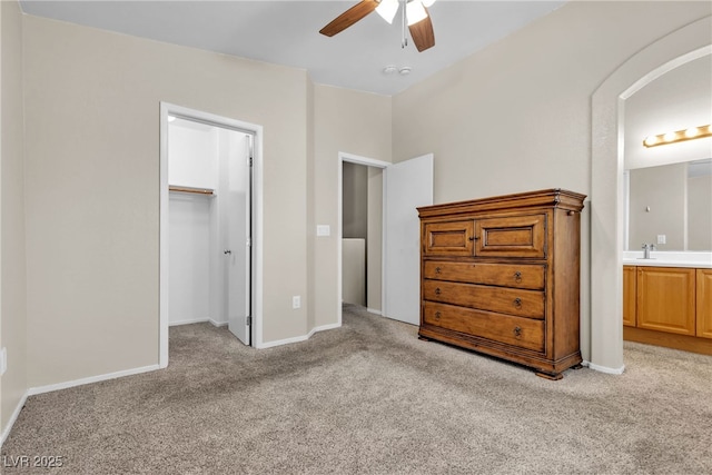 unfurnished bedroom featuring light carpet, a spacious closet, a closet, and ensuite bathroom