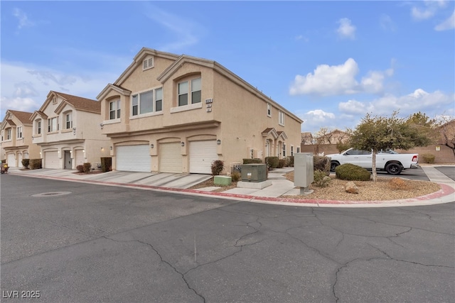 view of property with stucco siding, a residential view, and an attached garage