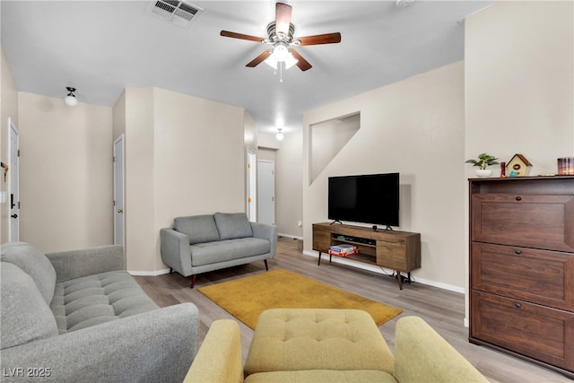 living room with ceiling fan, visible vents, baseboards, and light wood-style flooring