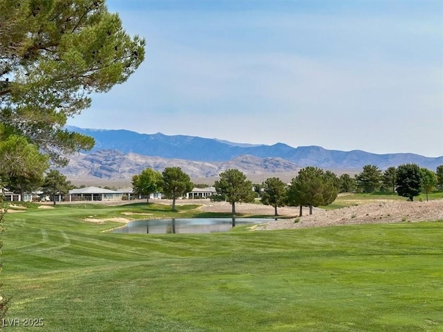 view of home's community with a water and mountain view and a lawn