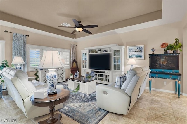 living room with a raised ceiling and ceiling fan