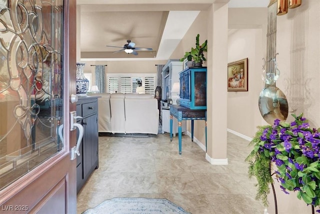 entryway with ceiling fan and a tray ceiling