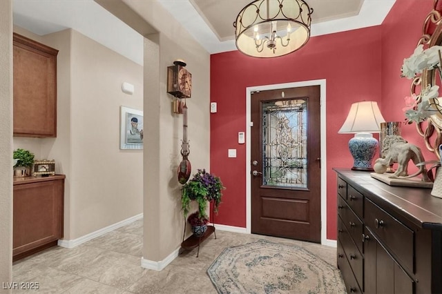 foyer featuring an inviting chandelier and a tray ceiling