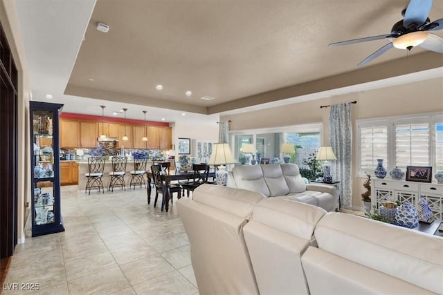 tiled living room featuring ceiling fan and a tray ceiling