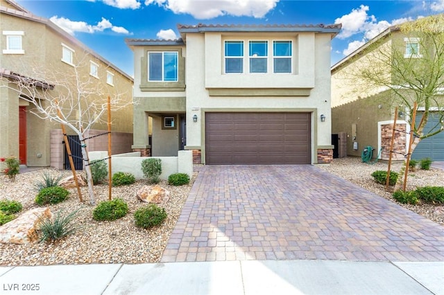 view of front of property featuring a tiled roof, decorative driveway, an attached garage, and stucco siding