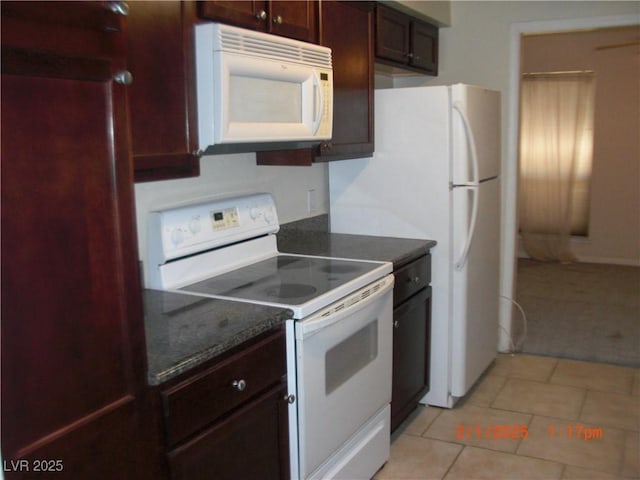 kitchen featuring light tile patterned floors, white appliances, and dark stone counters