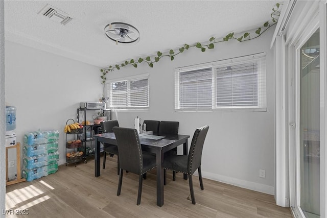 dining area featuring light hardwood / wood-style flooring and a textured ceiling