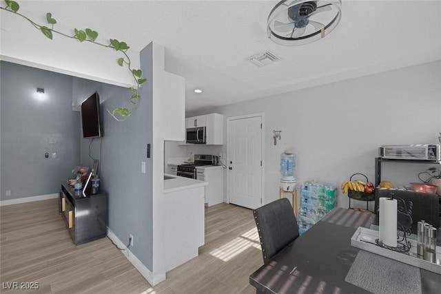 interior space featuring light hardwood / wood-style floors, white cabinets, and appliances with stainless steel finishes