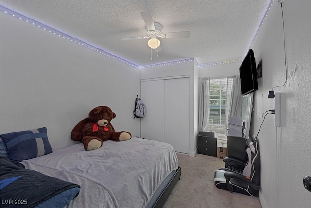 carpeted bedroom with ceiling fan, a closet, and a textured ceiling