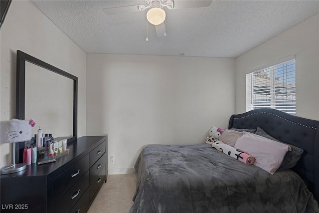 bedroom with ceiling fan, light carpet, and a textured ceiling