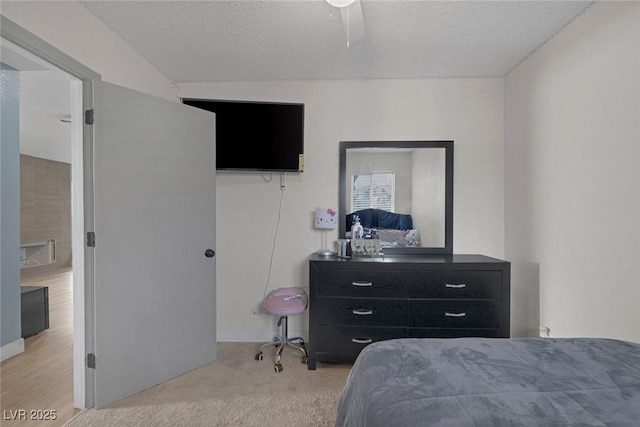 bedroom with ceiling fan, light colored carpet, and a textured ceiling